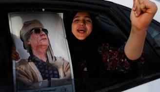 Una ragazza non identificata urla e tiene in mano un ritratto del leader libico Muammar Gheddafi mentre partecipa a una manifestazione accanto al complesso Bab al-Aziziya di Gheddafi a Tripoli, in Libia.